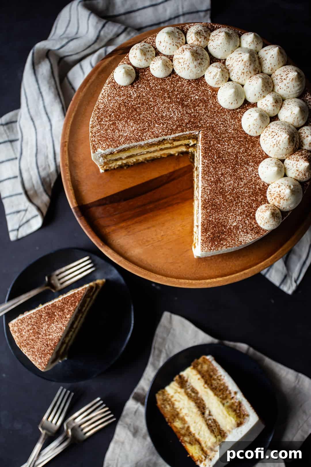 Slices of terimisu cake served on dark ceramic plates.