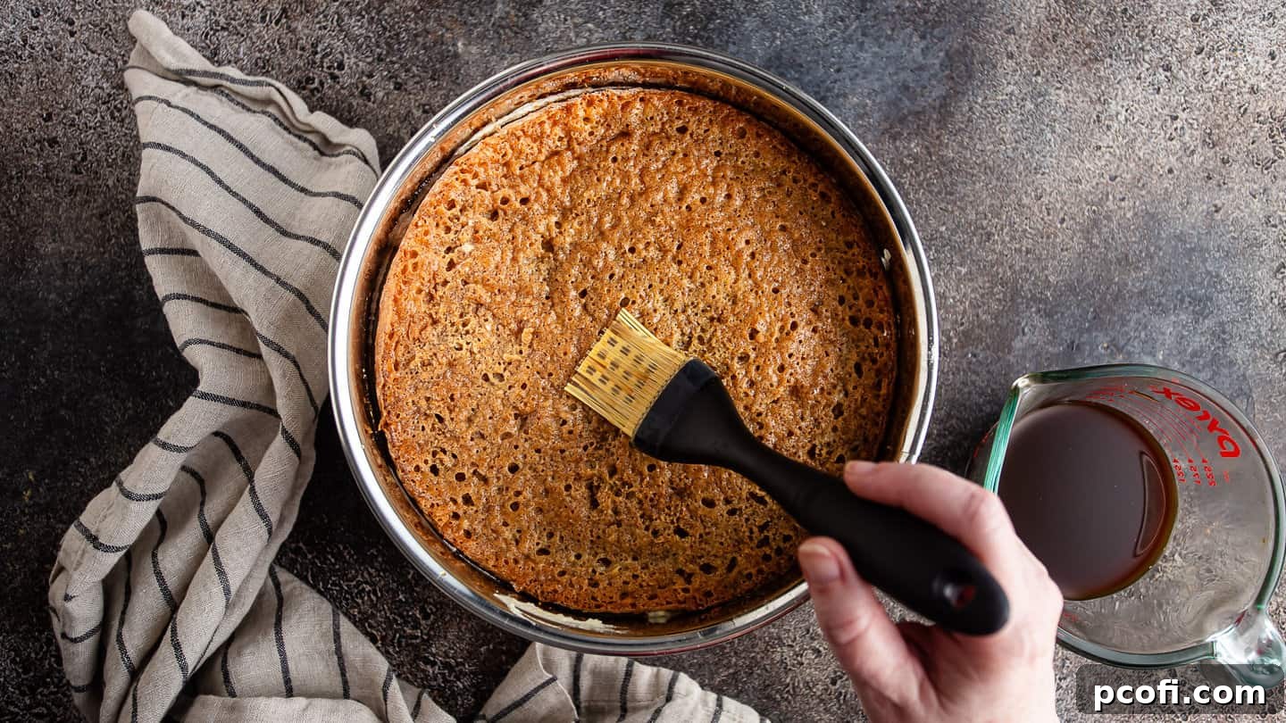 Soaking genoise cake with coffee syrup, using a pastry brush.
