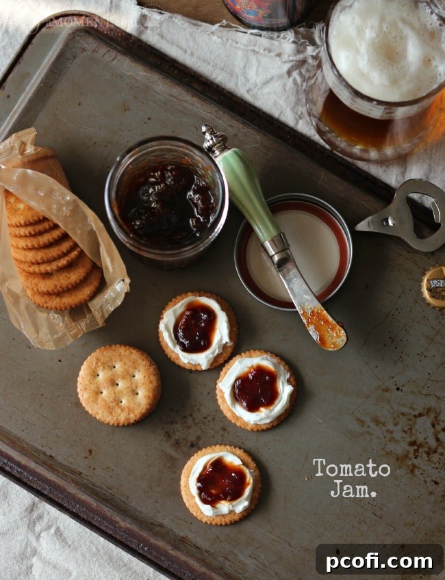 Rich, deep red tomato jam simmering in a pot on the stovetop, close-up