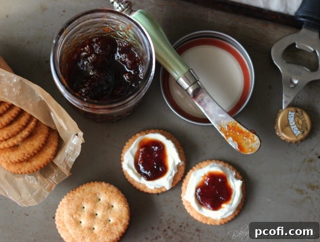 Three glass jars filled with homemade tomato jam, some with lids, cooling on a wire rack