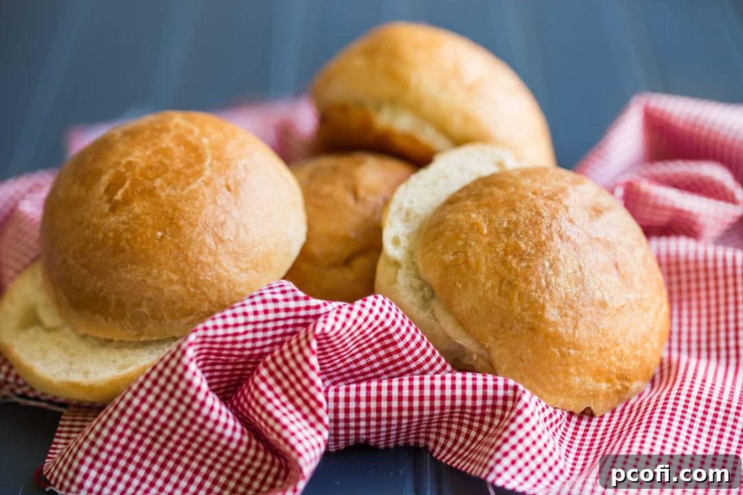 A large stack of freshly baked brioche hamburger buns on a wooden board