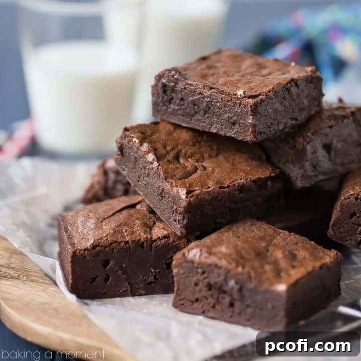 Brownies on a wood plate with a glasses of milk in the background.