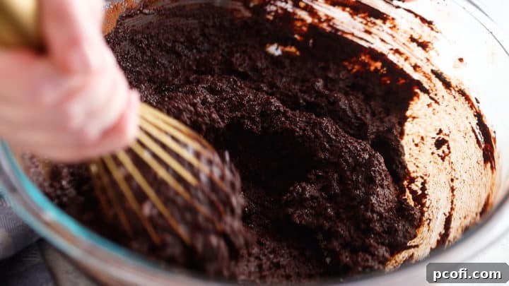 Mixing sugar, cocoa, and melted butter together to make brownies from scratch.