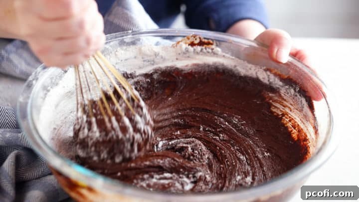 Adding dry ingredients to a brownie recipe.
