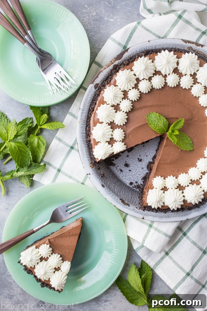 Beautifully plated slice of Mint Chocolate Icebox Pie, garnished with a sprig of fresh mint, highlighting the smooth texture of the mousse and the crisp crust. A perfect dessert for entertaining or a personal indulgence.