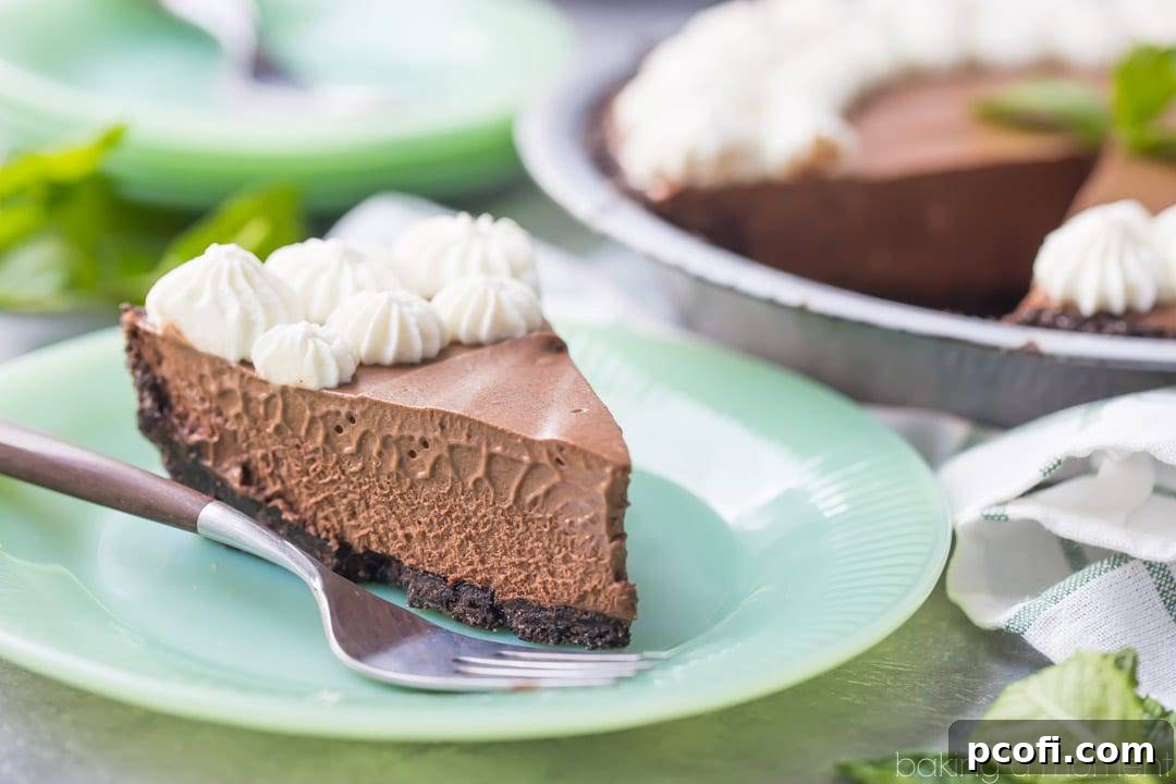 A whole Mint Chocolate Icebox Pie, showcasing its inviting presentation with decorative whipped cream and fresh mint leaves. The perfect centerpiece for any dessert table.
