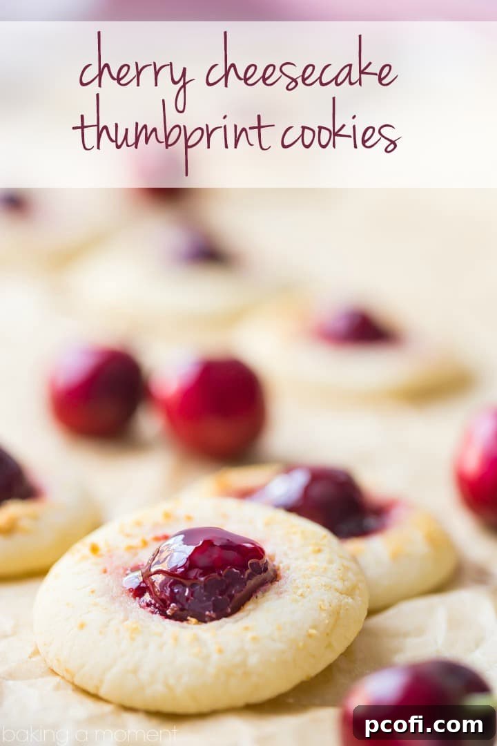 Close-up of Cherry Cheesecake Thumbprint Cookies showcasing their vibrant red cherry centers and delicate graham cracker edges, sitting on a rustic wooden board.