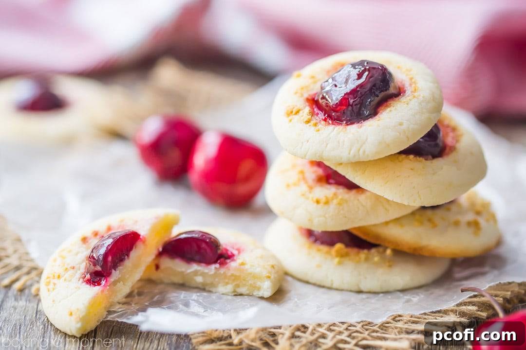 An overhead shot of multiple Cherry Cheesecake Thumbprint Cookies, highlighting their uniform shape, golden edges, and generous cherry filling.