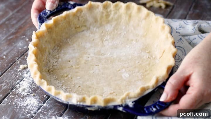 A perfectly formed unbaked pie crust resting in a pie dish, featuring a beautifully crimped edge, awaiting its filling.