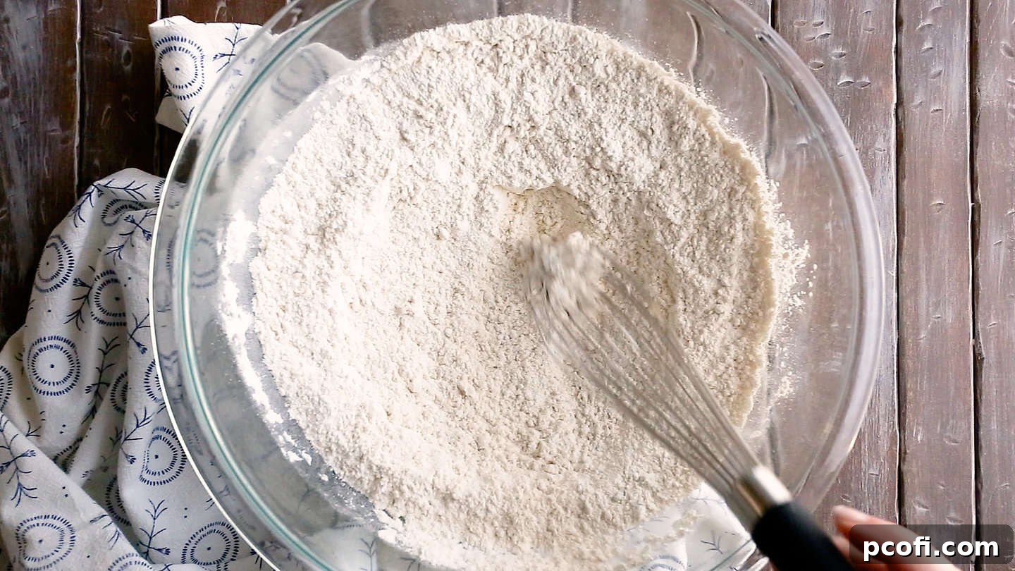 Whisking all-purpose flour and kosher salt together in a large glass bowl to ensure even distribution.