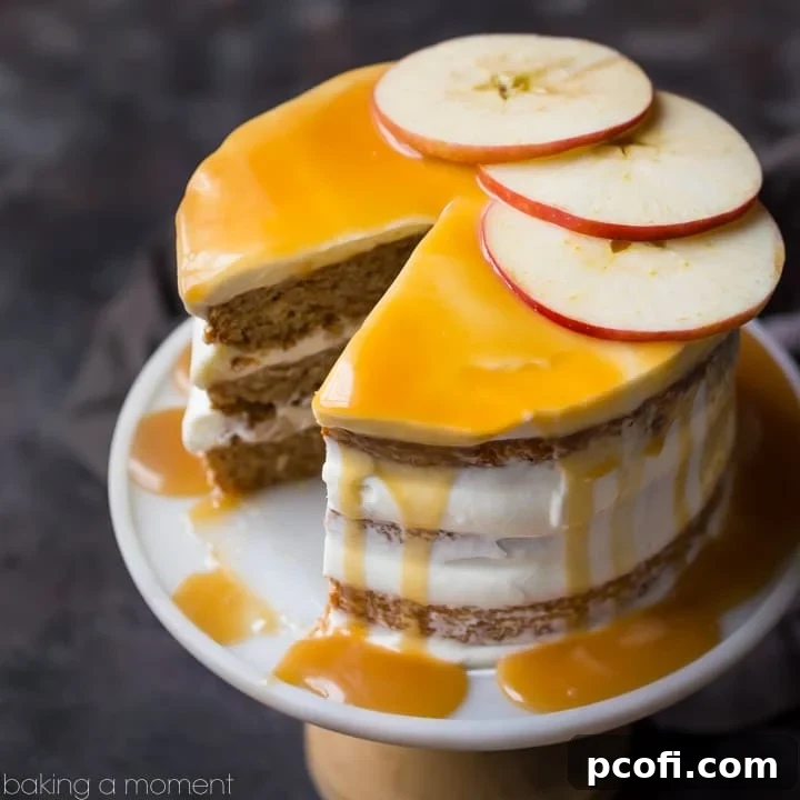 A stunning triple-layer apple honey cake, generously frosted with cream cheese and drizzled with glistening honey caramel, presented elegantly on a cake stand with fresh apple slices for garnish.