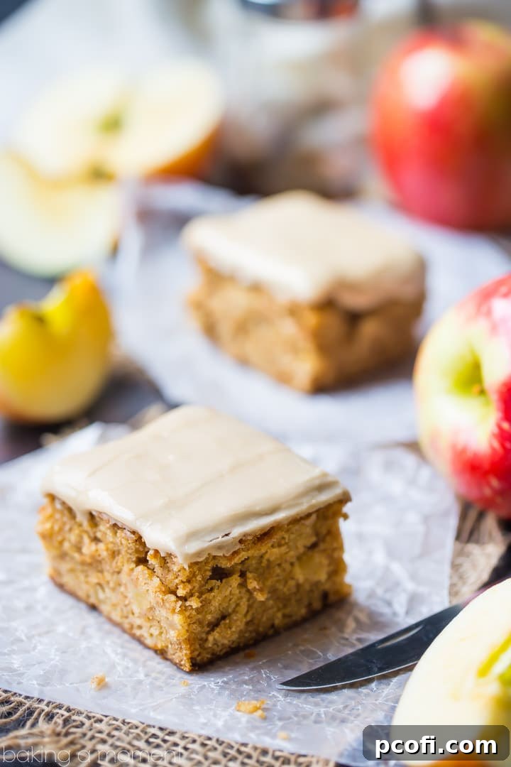 Close-up of a soft, cake-y apple blondie with visible apple chunks and a sweet maple glaze, ready to be enjoyed as a fall dessert.