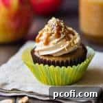 A delicious caramel apple cupcake with salted caramel buttercream, caramel drizzle, and chopped peanuts.
