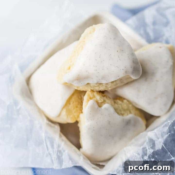 A basket overflowing with freshly baked, glazed petite vanilla bean scones, set on a soft blue cloth, evoking a cozy breakfast or brunch scene.