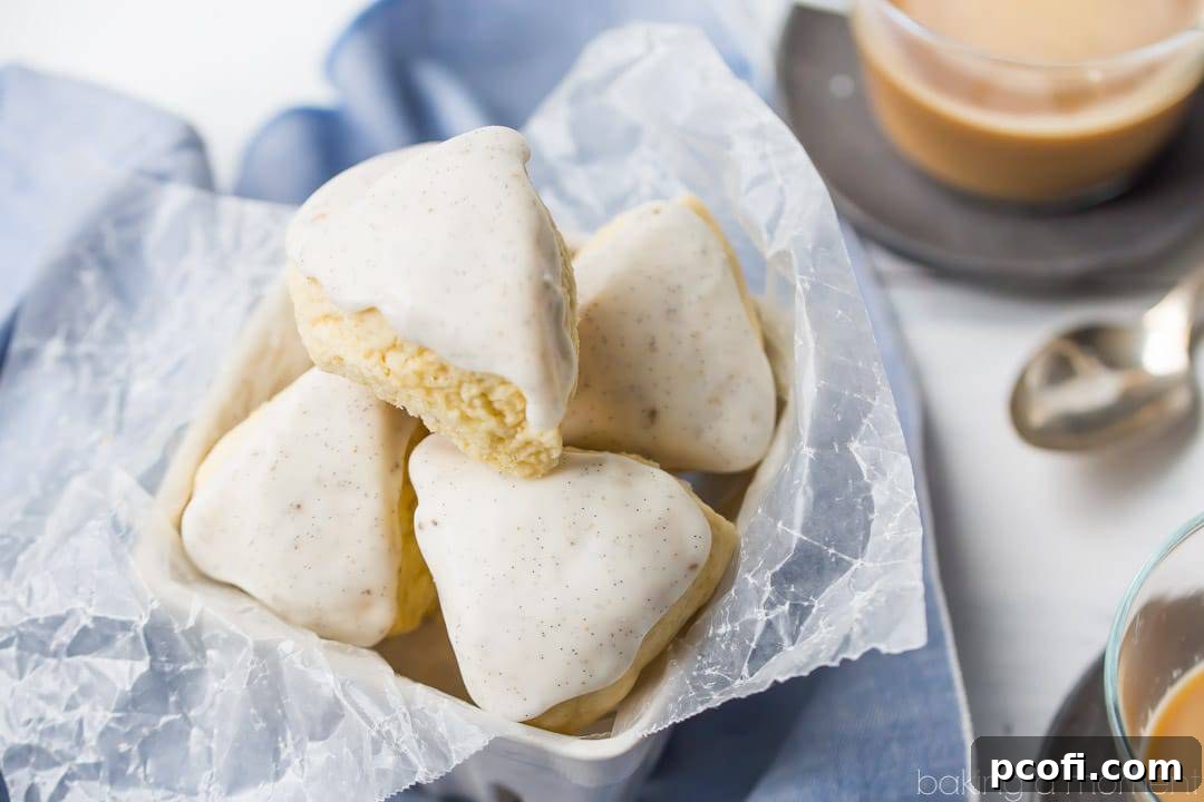 An inviting scene featuring glazed petite vanilla bean scones in a woven basket, accompanied by cups of coffee and elegant spoons, symbolizing a perfect breakfast setting.
