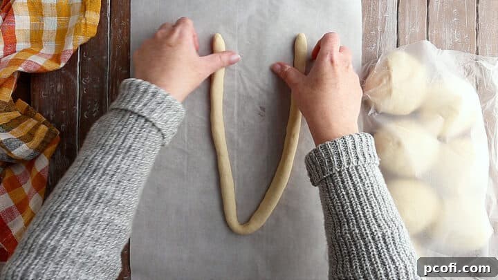 Soft pretzel dough being formed into a 'U' shape, the first step in creating the classic pretzel twist.