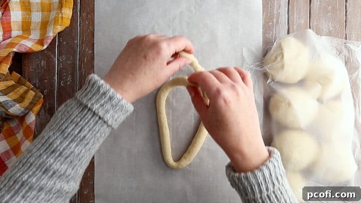 The ends of the soft pretzel dough being pulled down and towards the center, intertwining to create the traditional pretzel knot.