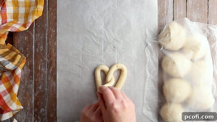 A close-up view of the final twisting motion for a homemade soft pretzel, ensuring a secure and aesthetic knot.