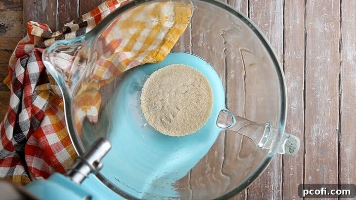 A large glass mixing bowl filled with a foamy yeast mixture, showing successful activation and readiness for dough making.