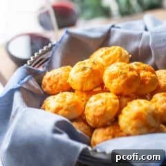 Basket of cheese puffs with glasses of wine in the background.