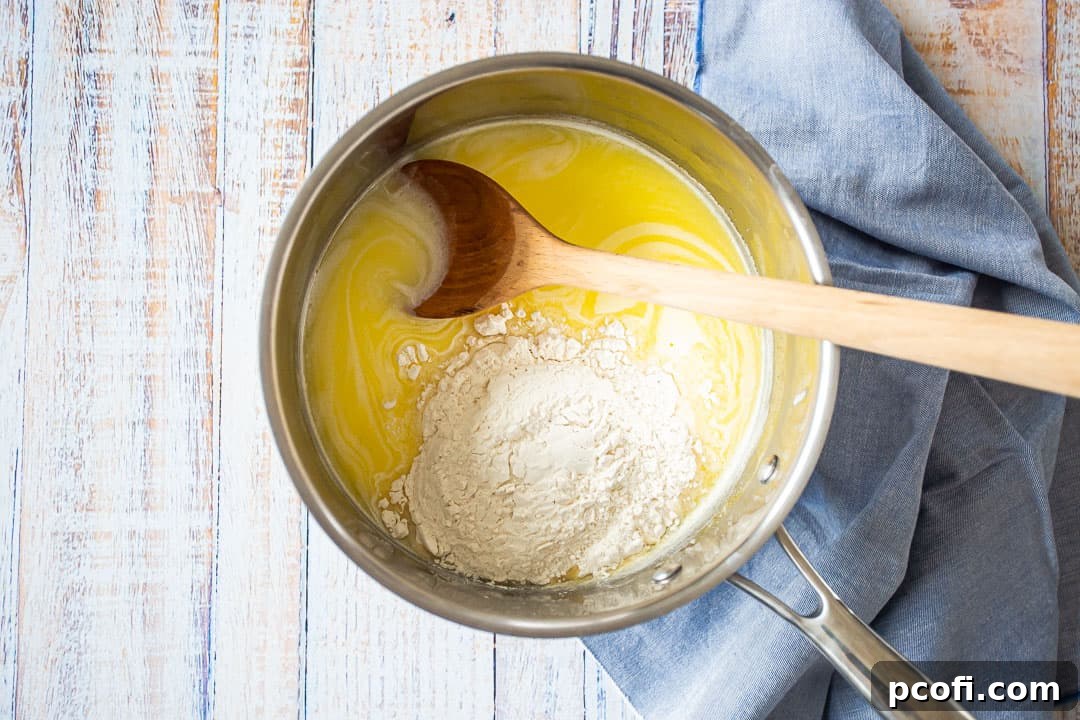 Flour being added to the hot liquid mixture in a saucepan to start forming pate a choux.