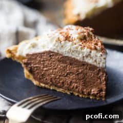 A tall slice of chocolate pie with whipped cream on a dark blue plate.