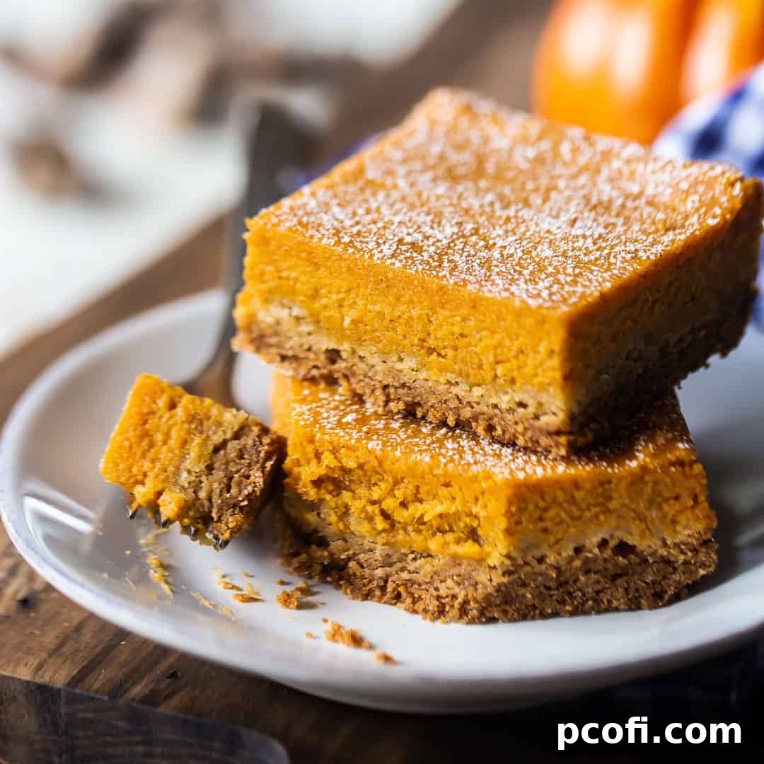 Delicious Pumpkin Gooey Butter Cake bars, artfully stacked on a white plate atop a rustic wood board.