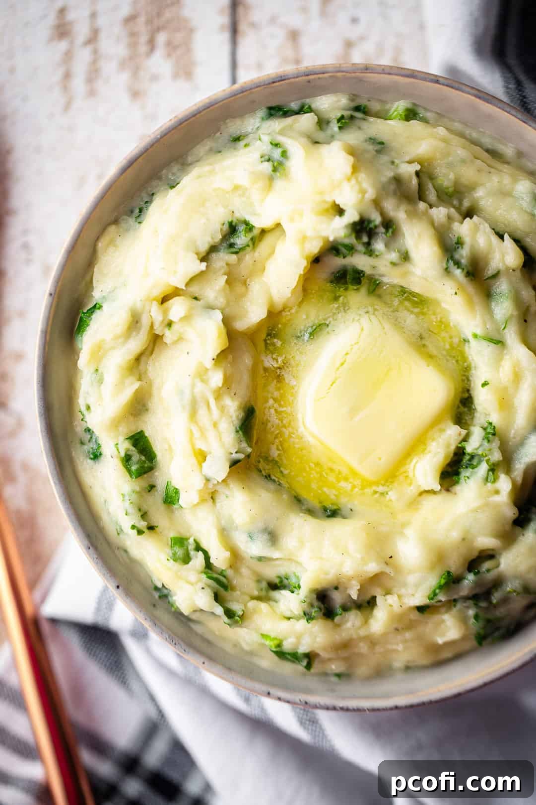 A serving bowl filled with creamy Cheesy Colcannon, garnished with a copper serving spoon, ready for a delicious meal.
