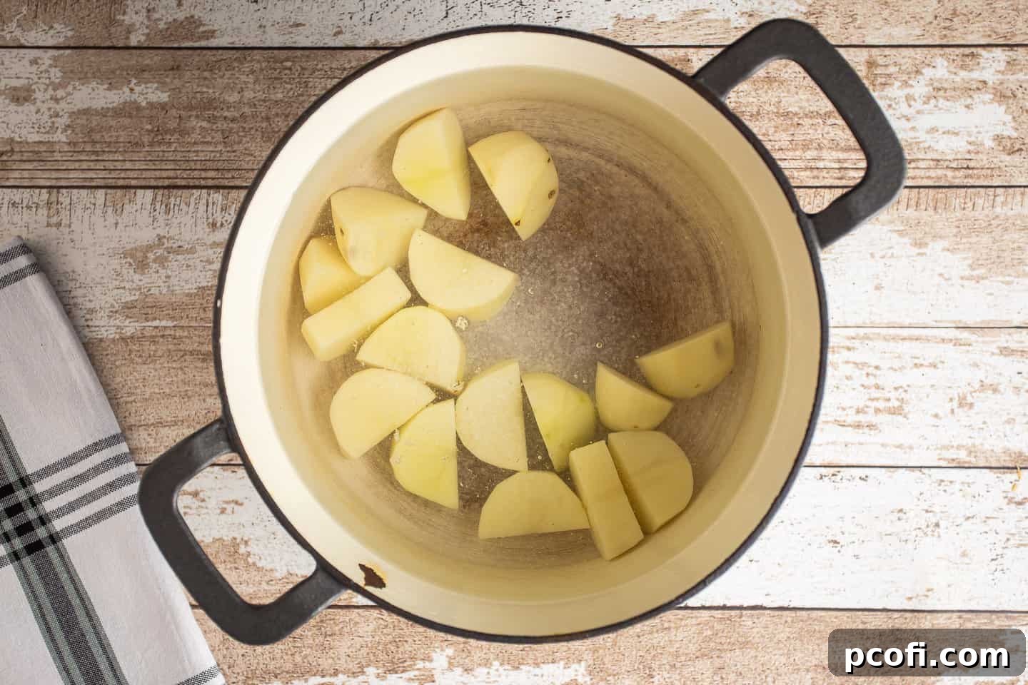 Potato chunks in a large pot, covered with cold, salted water before being placed on the stove.