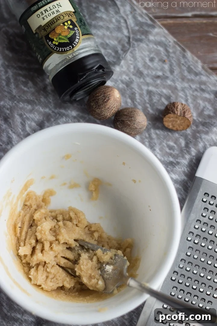 Ingredients for Hot Buttered Jamie: softened butter, brown sugar, and freshly grated nutmeg mixed in a small bowl with a fork, ready to be combined with whiskey and tea.