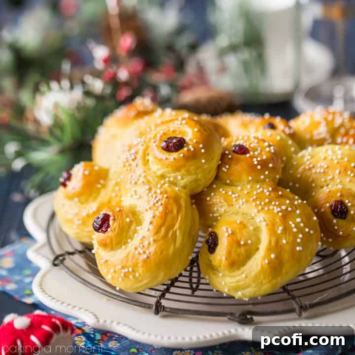 Golden saffron St. Lucia Buns in an "S" shape, lightly sprinkled with sugar and adorned with dried cranberries, resting on a cooling rack against a festive dark blue background with subtle Christmas decorations.