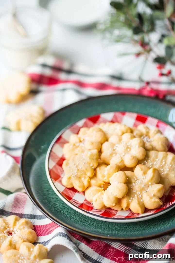 A collection of exquisite spritz cookies, beautifully textured and richly buttery, positioned perfectly for a holiday photo. These cookies are renowned for being light, crisp, and truly irresistible, epitomizing the festive season.