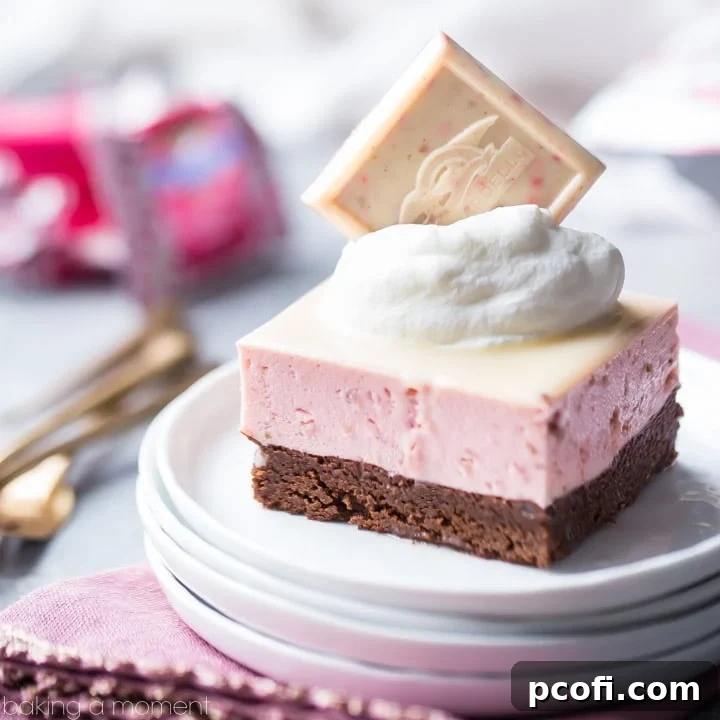 Chocolate Strawberry Mousse Bar: a layered dessert with rich chocolate torte, and a pale pink strawberry mousse drizzled with white chocolate glaze. Topped with whipped cream and a Ghirardelli Strawberry Bark SQUARE, beautifully plated on a pink napkin with gold forks.