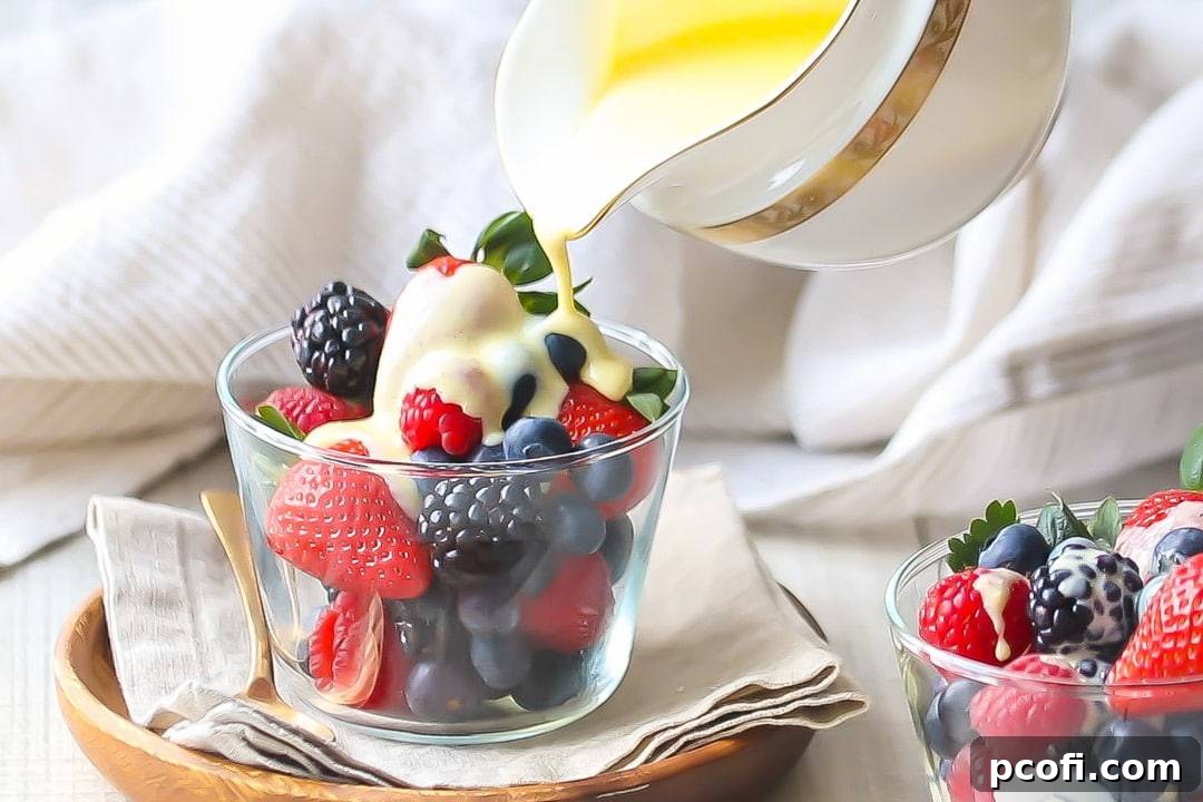 Creme Anglaise: rich, velvety vanilla custard sauce being poured over a bowl of berries, sitting on a linen napkin with a gold spoon off to one side.