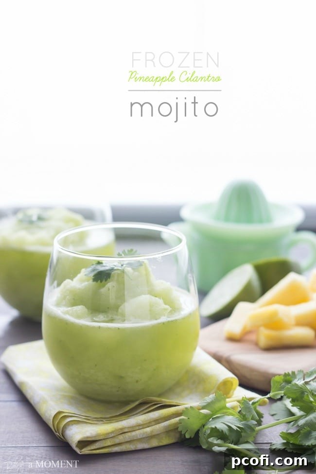 A close-up of a refreshing Frozen Pineapple Cilantro Mojito in a glass, with vibrant green and yellow hues, garnished with fresh cilantro. | Baking a Moment
