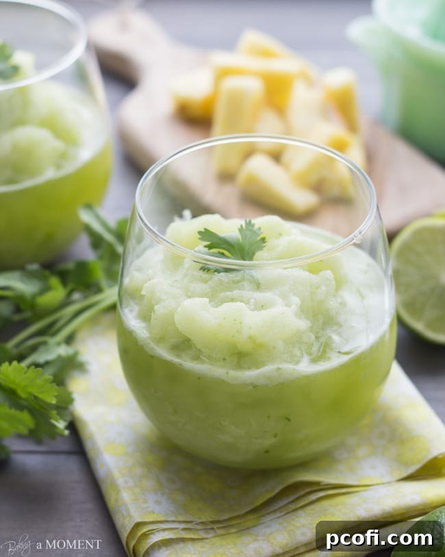 A freshly blended Frozen Pineapple Cilantro Mojito, close-up to show the smooth, frosty texture, ready to be enjoyed as a cool, invigorating drink. | Baking a Moment
