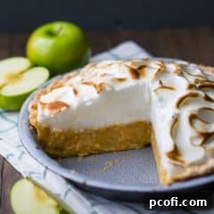 A pie dish of Irish apple amber, on a dark background with green apples in the background.