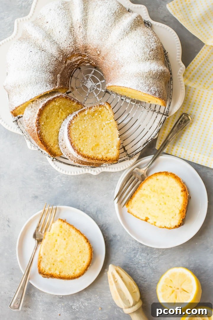 An inviting overhead shot of a sliced lemon pound bundt cake on a cooling rack over a yellow napkin, with individual cake slices arranged on white plates alongside silver forks, ready to be enjoyed.