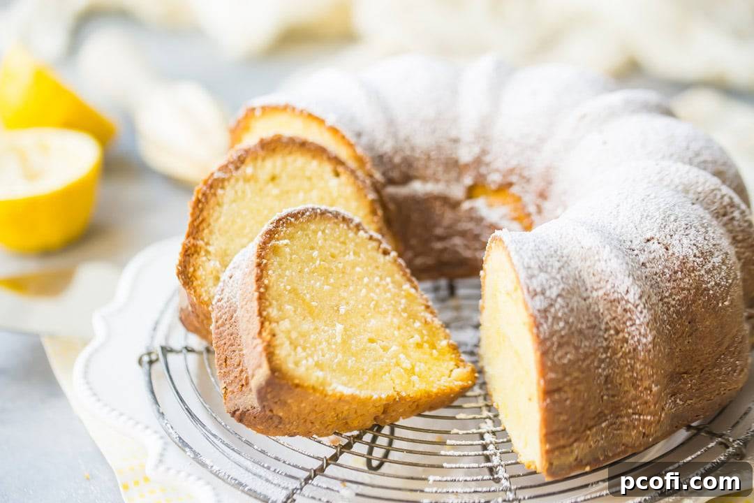 A beautifully moist lemon pound bundt cake, lightly dusted with powdered sugar, resting on a wire cooling rack over a cheerful yellow napkin, highlighting its perfect golden hue and tender crumb.