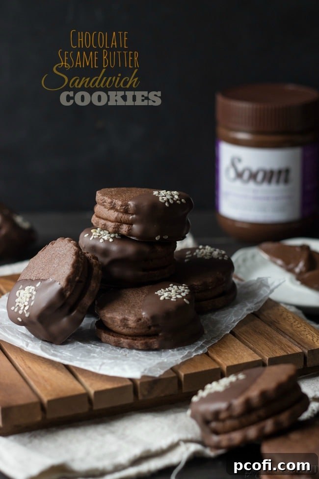 Chocolate Sesame Butter Sandwich Cookies stacked, showing the creamy filling and dark chocolate dip.
