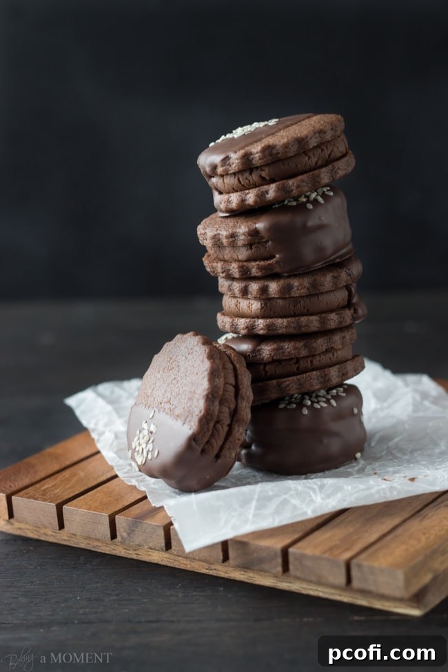 A plate of freshly dipped Chocolate Sesame Butter Sandwich Cookies with sesame seed garnish.