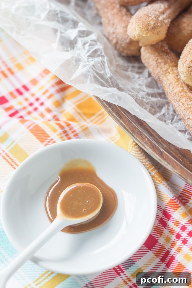 Homemade Cajeta bubbling gently in a pot on the stove, mid-cooking process.