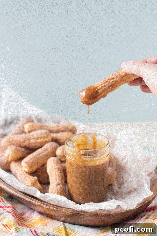 Homemade Cajeta with Baked Churros - A close-up shot of a hand dipping a baked churro into a bowl of cajeta.