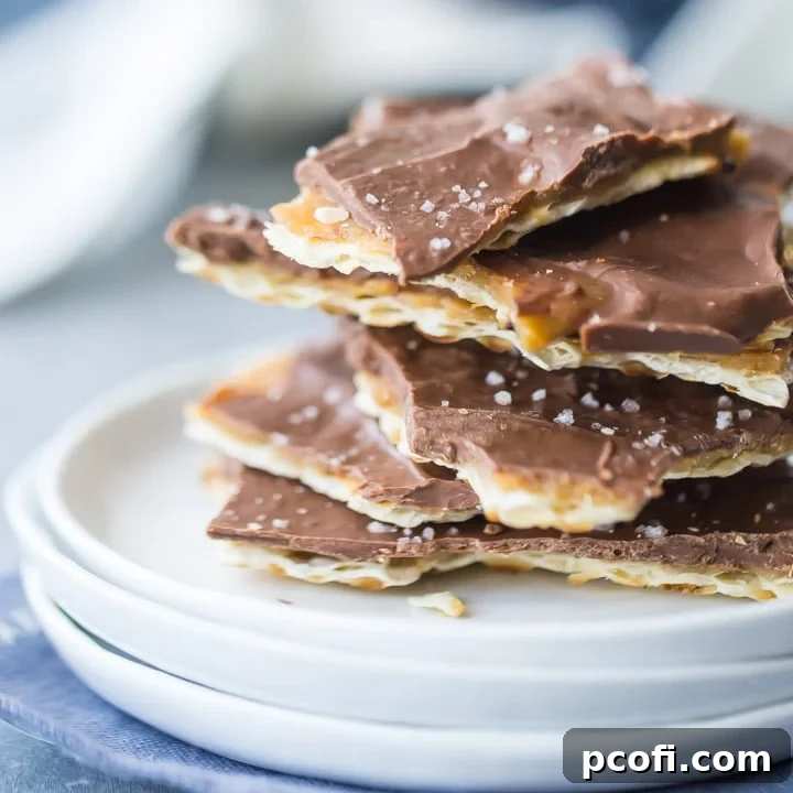 Square image of a stack of matzo toffee on a small white plate, with a blue napkin underneath.