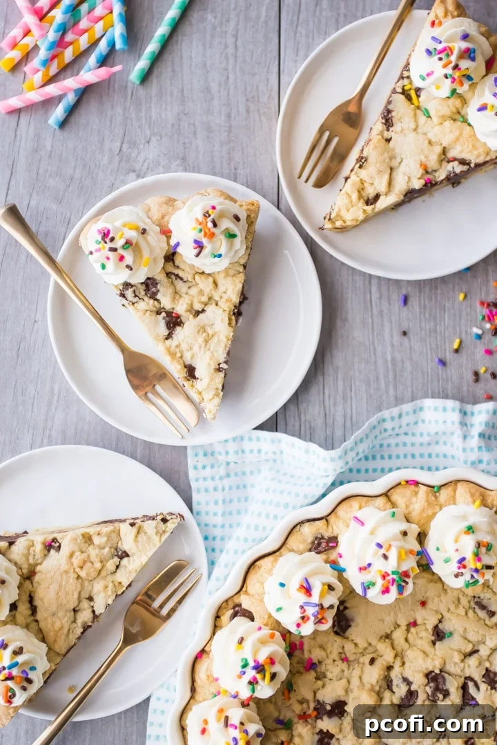 Several slices of giant chocolate chip cookie cake, adorned with gold forks and rainbow sprinkles, arranged on individual plates for serving.