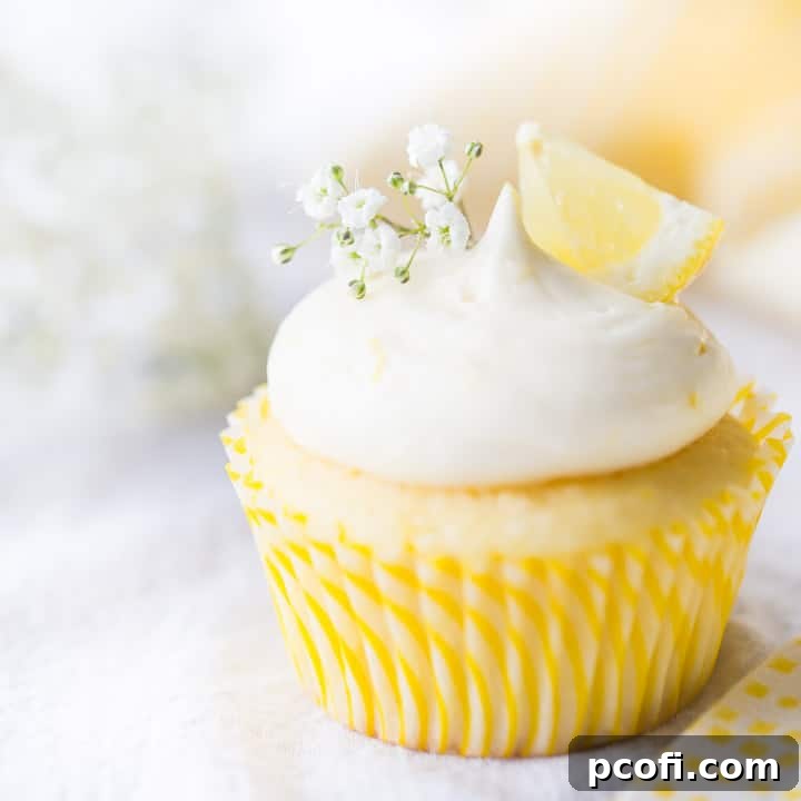 Lemon cupcake with lemon curd filling & lemon cream cheese frosting, garnished with baby's breath and a wedge of fresh lemon, ready to be enjoyed.