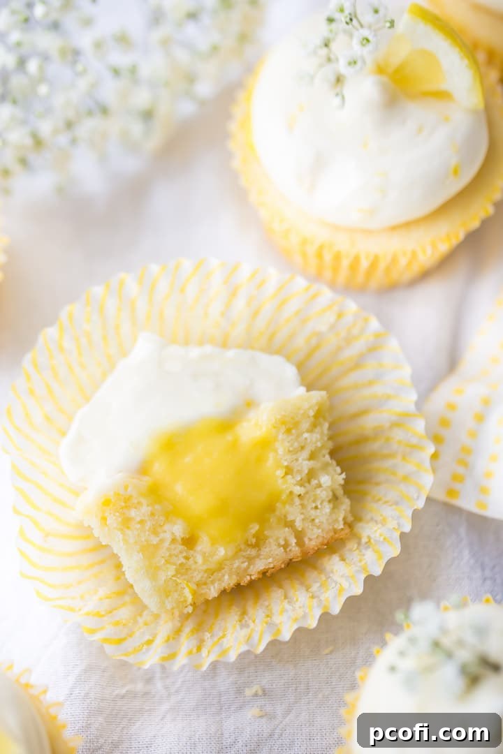 Overhead view of a lemon cupcake cut in half, revealing the luscious lemon curd filling and generous swirl of cream cheese frosting.