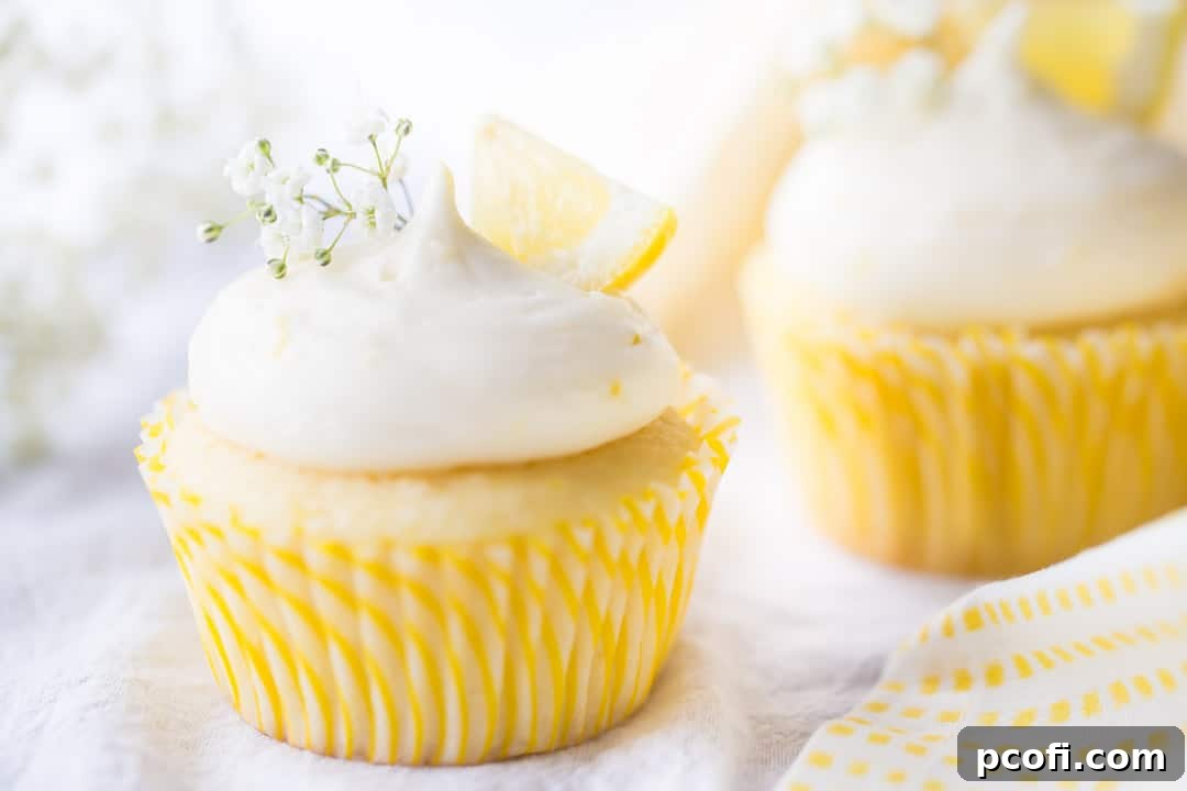 Horizontal image of beautifully arranged lemon cupcakes, featuring a lemon curd filling and lemon cream cheese frosting, artistically garnished with fresh lemon wedges and delicate baby's breath.