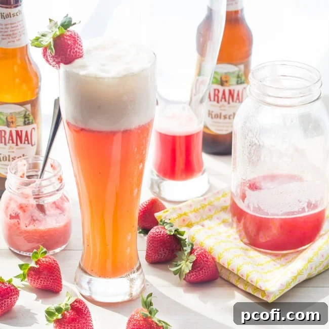 Refreshing Strawberry Rhubarb Shandy in a tall glass, garnished with a slice of lime and strawberry, perfect for summer.