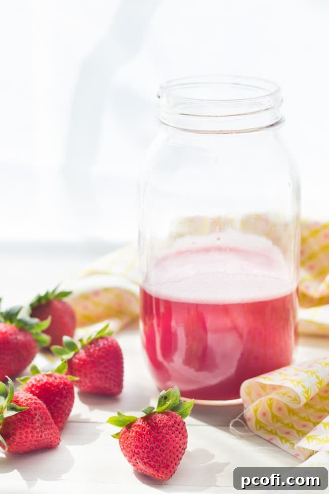 Homemade Rhubarb Syrup, a beautiful red-pink liquid, showcased in a glass jar, ready to be used in refreshing drinks.